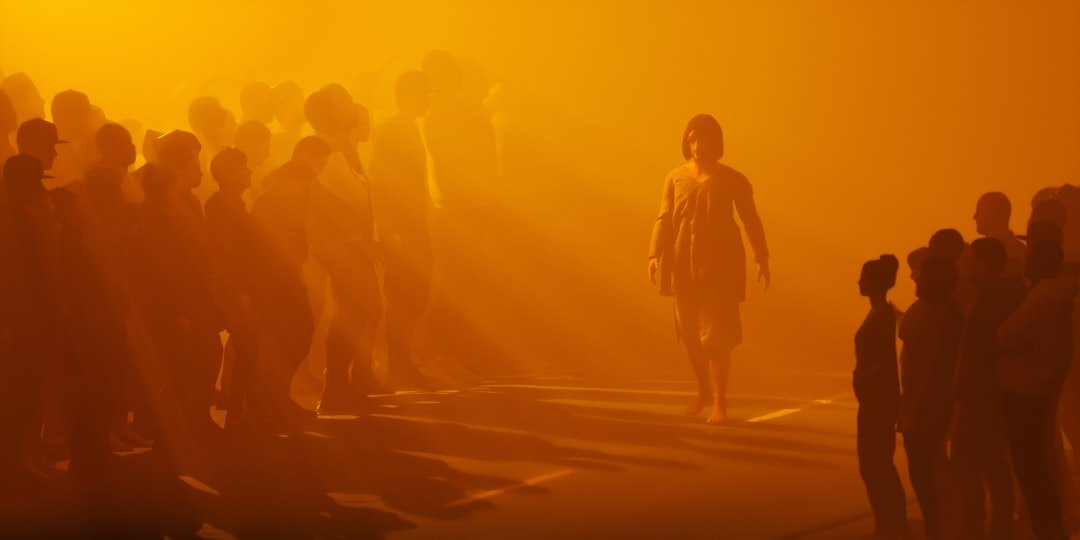 Fashion runway show with dramatic lighting and audience silhouettes